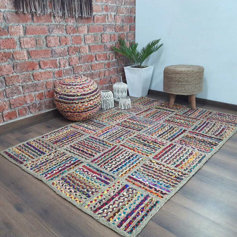 Handwoven braided natural jute and cotton chindi rug with patchwork texture in earthy tones, shown on a living room floor